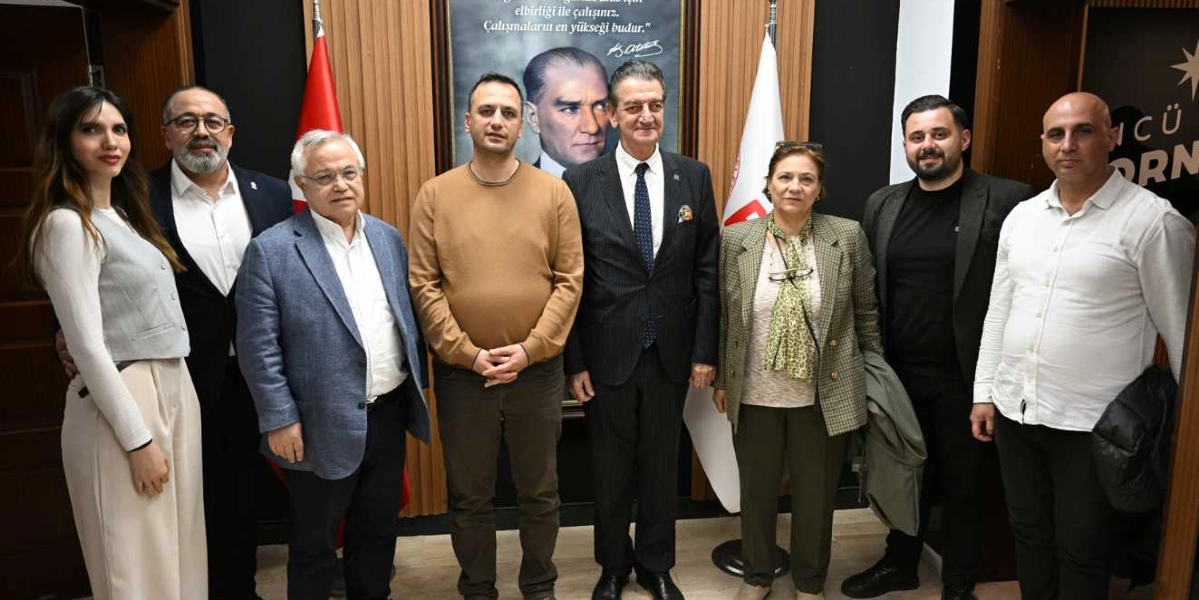Atatürkçü Düşünce Derneği Bornova Şubesi'nde bir araya gelen sekiz kişilik grup, arka planda Mustafa Kemal Atatürk'ün portresi ve Türk bayraklarının önünde yan yana durarak poz veriyor. Grupta farklı yaş ve giyim tarzlarına sahip kadın ve erkekler bulunuyor; merkezde takım elbiseli bir beyefendi yer alırken, diğer katılımcılar günlük ve yarı resmi kıyafetlerle eşlik ediyor.