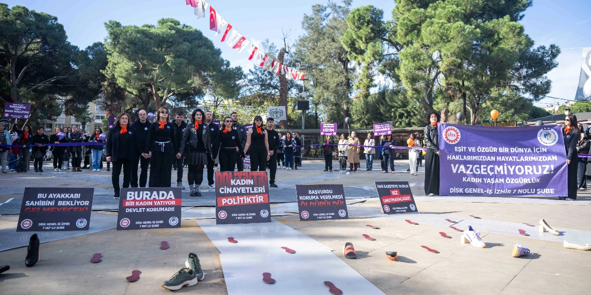 Bornova'da düzenlenen 25 Kasım Kadına Yönelik Şiddetle Mücadele Günü etkinliğinde, siyah kıyafetler giymiş bir grup kadın ve erkek, ellerinde 
