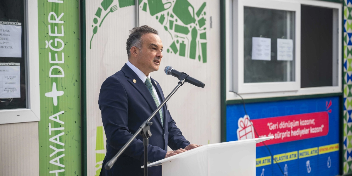 Koyu renk takım elbiseli ve yeşil kravatlı bir yetkili, üzerinde 