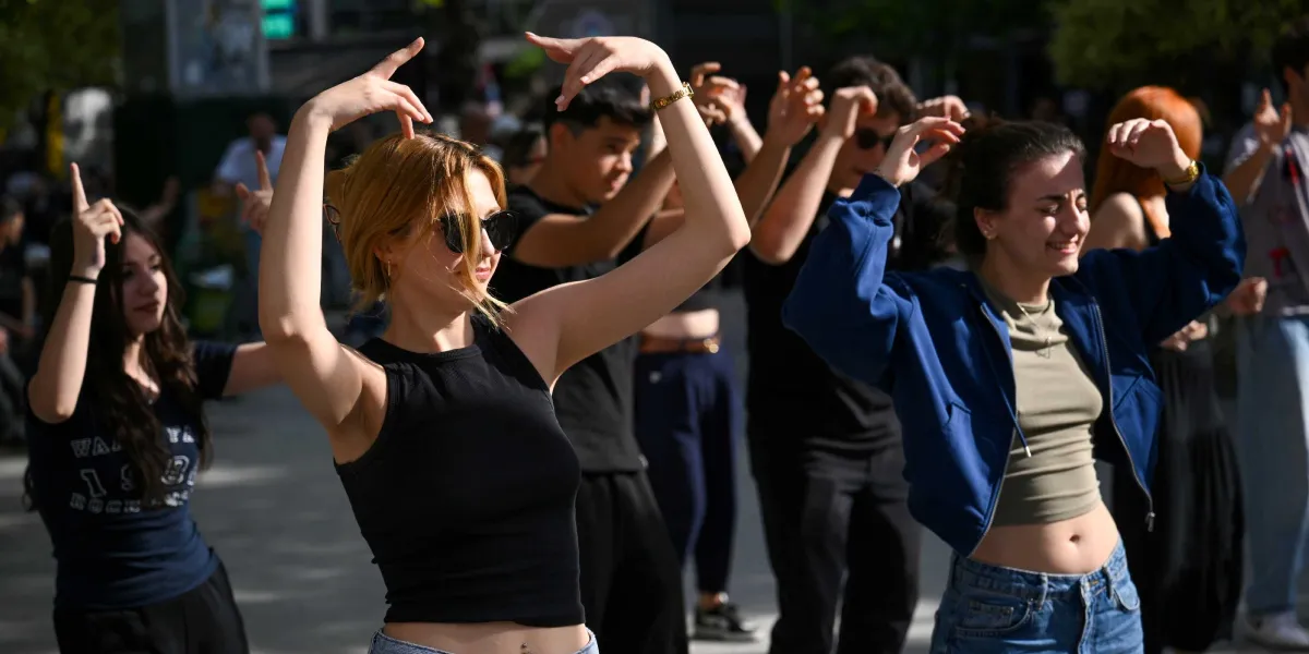 Bornova sokaklarında bir araya gelen bir grup genç, güneşli bir havada müzik eşliğinde dans ediyor. Ön planda siyah kolsuz bir bluz ve güneş gözlüğü takan sarışın bir genç kadın ile mavi ceketli ve kot pantolonlu başka bir genç kadın, kollarını havaya kaldırarak neşeyle dans ediyor. Arka planda ise aynı ritimle hareket eden diğer gençler yer alıyor.
