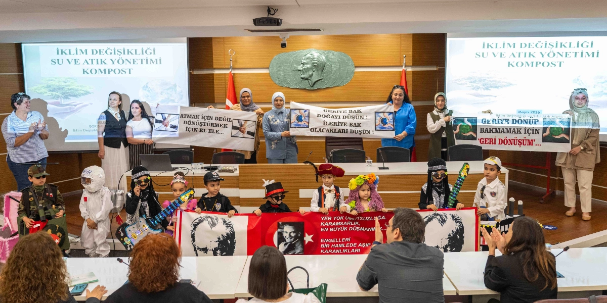 Bornova Belediyesi’nde düzenlenen, iklim değişikliği, su ve atık yönetimi konulu etkinlikte, çeşitli kostümler giymiş çocuklar ve yetişkinler bir araya gelmiş. Arka planda, üzerinde 