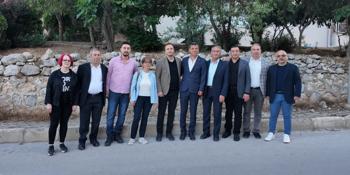 Açık havada, taş duvar ve ağaçların önünde yan yana duran, aralarında Bornova İzyuva bölgesi için çözüm arayışında olan yerel yöneticilerin ve temsilcilerin bulunduğu on kişilik grup.