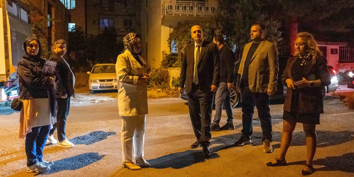 Gece vakti bir sokakta bir araya gelmiş, aralarında takım elbiseli bir erkeğin de bulunduğu altı kişilik bir grup, bir konu hakkında konuşurken görülüyor. Grubun merkezinde yer alan takım elbiseli ve kravatlı kişi, etrafındaki kişilerle etkileşim halindeyken, diğerleri dikkatle onu dinliyor. Arka planda park halindeki araçlar ve binalar seçiliyor.