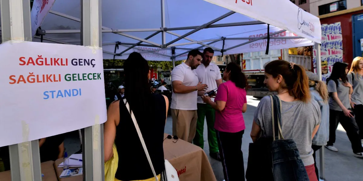 Bornova Belediyesi tarafından kurulan beyaz bir çadırın önünde, üzerinde 