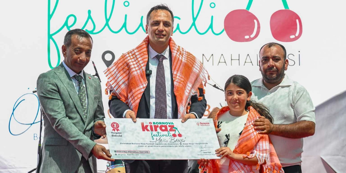 Bornova Kiraz Festivali kapsamında düzenlenen En Güzel Kiraz yarışmasında dereceye giren bir genç kıza, Bornova Belediye Başkanı Ömer Eşki ve beraberindekiler tarafından ödül belgesi takdim ediliyor. Arka planda festival logosu ve kiraz görsellerinin yer aldığı beyaz bir fon bulunurken, katılımcıların omuzlarında yöresel turuncu-beyaz desenli şallar yer alıyor.