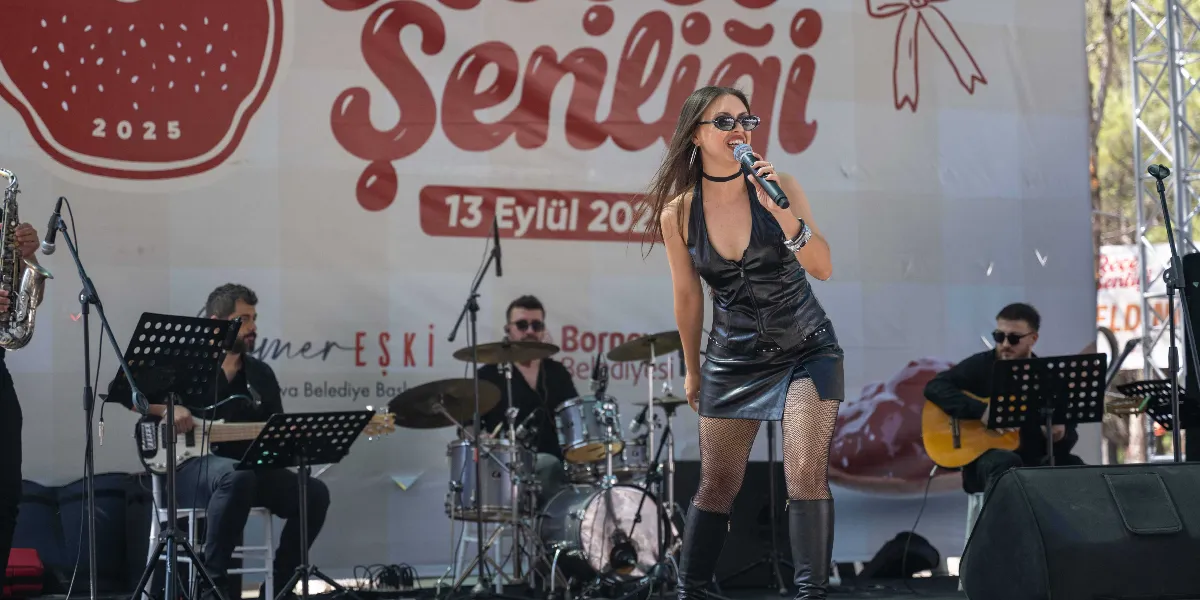 Yakaköy'de düzenlenen Türkiye'nin İlk Reçel Şenliği'nde, sahne üzerinde şarkı söyleyen güneş gözlüklü kadın soliste, arkasında bateri, gitar ve saksafon çalan müzisyenlerden oluşan bir grup eşlik ediyor. Arka planda üzerinde 