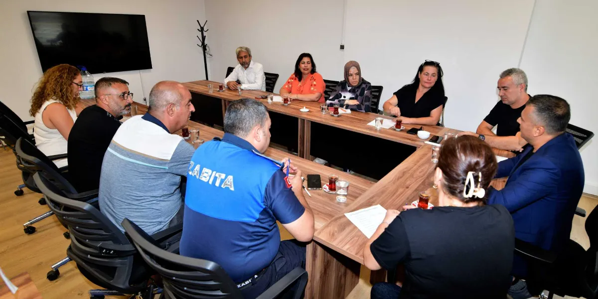 U-şeklinde bir masa etrafında toplanmış, aralarında üzerinde 