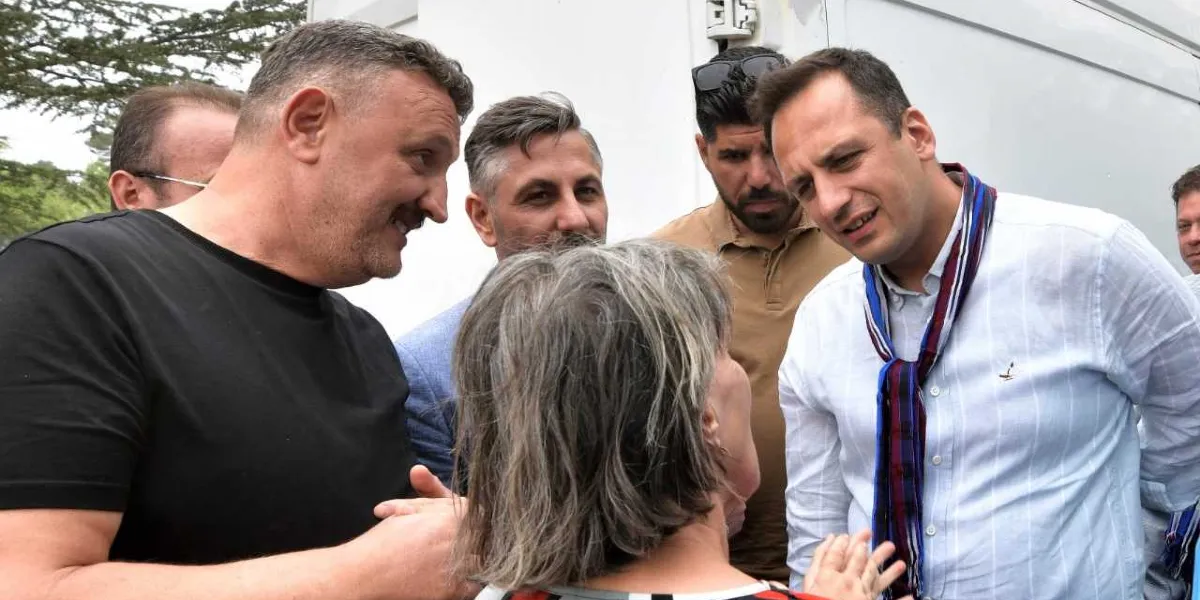 Beyaz gömlekli ve boynunda Karadeniz yöresine özgü desenli bir şal bulunan Başkan Filiz Ceritoğlu Sengel, siyah tişörtlü bir adam ve çevresindeki diğer kişilerle samimi bir şekilde sohbet ediyor.
