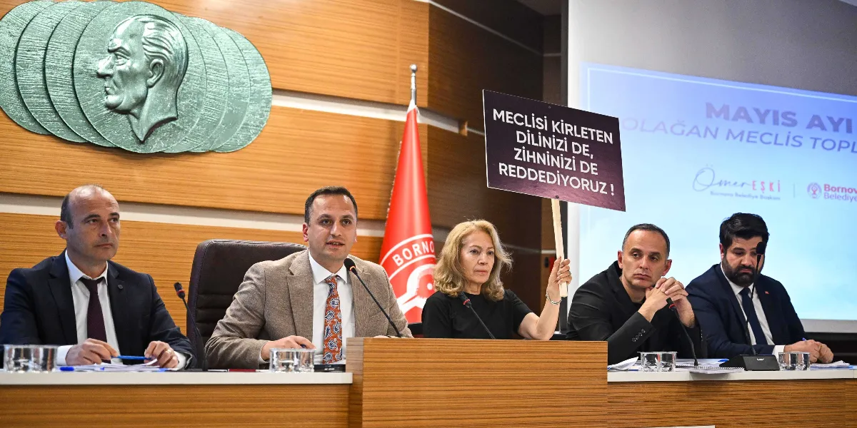 Bornova Belediyesi meclis toplantısında, masada oturan beş kişilik bir grup yer alıyor. Gruptaki kadın üye, üzerinde 