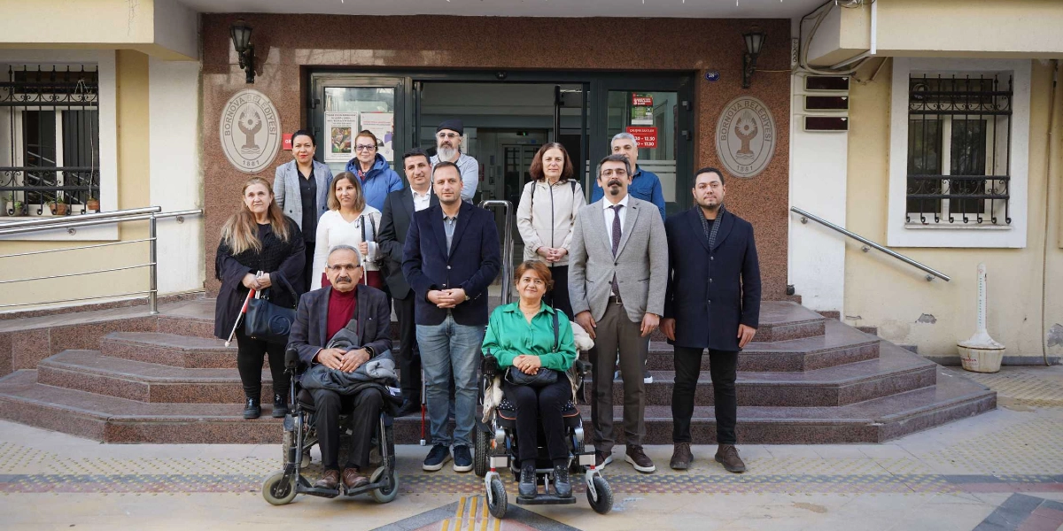Bornova Belediyesi binasının girişindeki merdivenlerin önünde duran, aralarında tekerlekli sandalye kullanan bireylerin de bulunduğu Kent Konseyi üyeleri ve Bornova Belediye Başkanı Ömer Eşki'nin yer aldığı toplu fotoğraf.