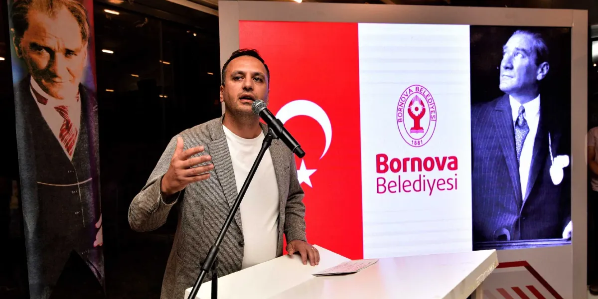 Bornova Belediye Başkanı Ömer Eşki, kürsüde mikrofon başında konuşma yaparken görülüyor. Arka planda Türk bayrağı, Bornova Belediyesi logosu ve Mustafa Kemal Atatürk'ün fotoğraflarının yer aldığı bir ekran bulunuyor.