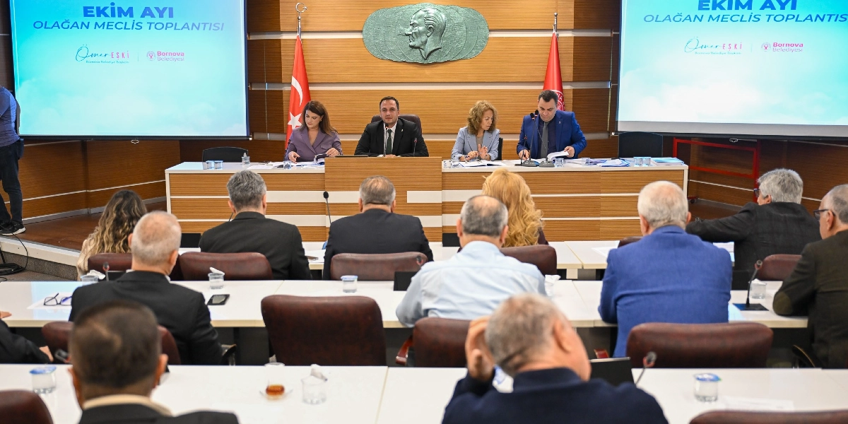 Bornova Belediyesi Ekim Ayı Olağan Meclis Toplantısı'nda, başkanlık divanında oturan dört yetkili ve onları dinleyen meclis üyeleri yer alıyor. Arka planda duvarda Atatürk rölyefi ve iki yanında Türk bayrakları bulunurken, yanlarda yer alan büyük ekranlarda 