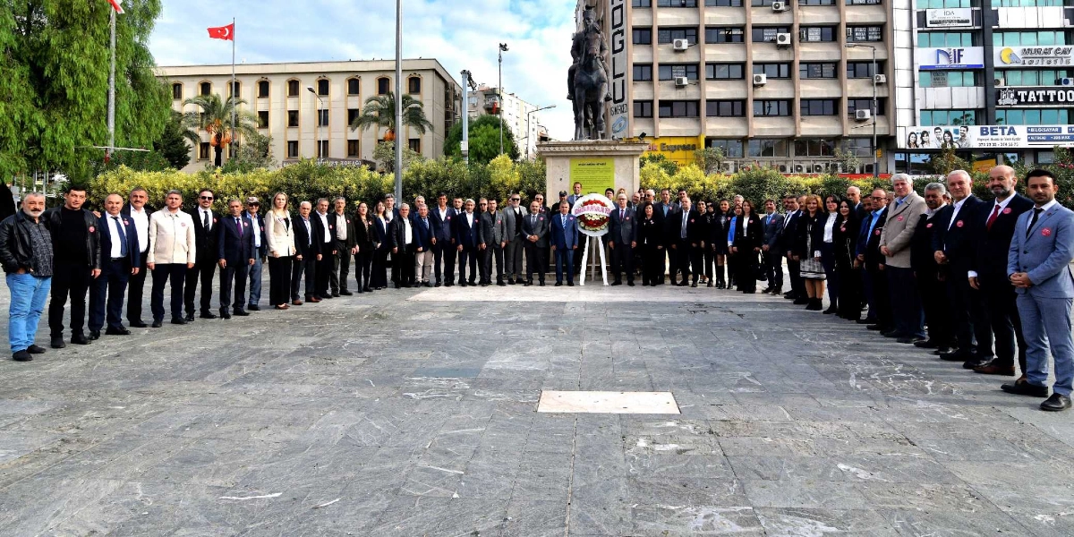 Bornova'da bir meydanda, Atatürk heykeli önünde yan yana dizilmiş, resmi kıyafetli kalabalık bir muhtar grubu, Muhtarlar Günü anma töreni kapsamında çelenk sunumu sonrası toplu halde poz veriyor.