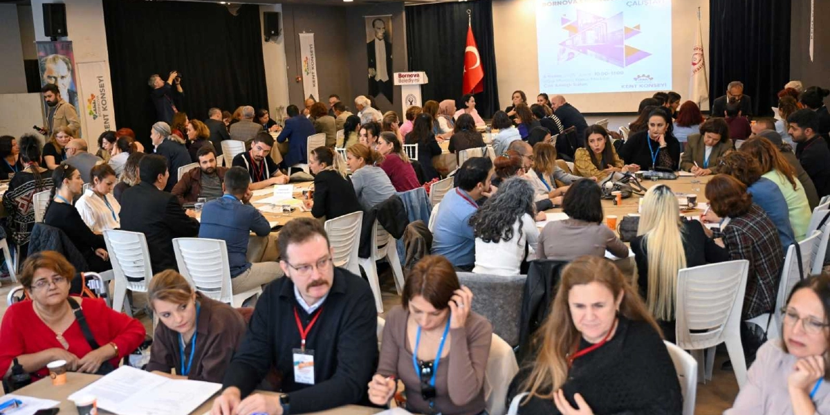 Bornova Kent Konseyi tarafından düzenlenen ve çok sayıda katılımcının yuvarlak masalar etrafında bir araya geldiği bir çalıştay toplantısı. Salonun ön kısmında üzerinde 