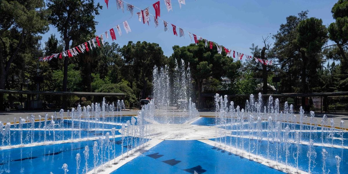 Bornova'da, zemininde yıldız deseni bulunan mavi renkli bir süs havuzundan yükselen su fıskiyeleri ve havuzun üzerinde gökyüzüne asılmış Türk bayrakları ile Atatürk posterlerinin bulunduğu ağaçlık bir park alanı.