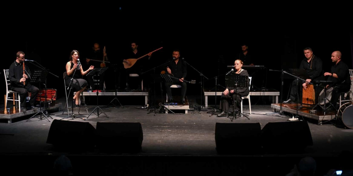 Siyah bir sahnede, tamamı siyah kıyafetler giymiş sekiz kişilik bir müzik grubu performans sergiliyor. Soldan sağa doğru; ney çalan bir erkek, mikrofon başında şarkı söyleyen bir kadın, yaylı bir enstrüman çalan bir kişi, bağlama çalan bir müzisyen, elinde gitar tutan bir erkek, mikrofon başında şarkı söyleyen başka bir kadın, klavye başında oturan bir kişi ve perküsyon çalan iki erkek yer alıyor. Müzisyenlerin önünde nota sehpaları ve mikrofonlar bulunuyor.