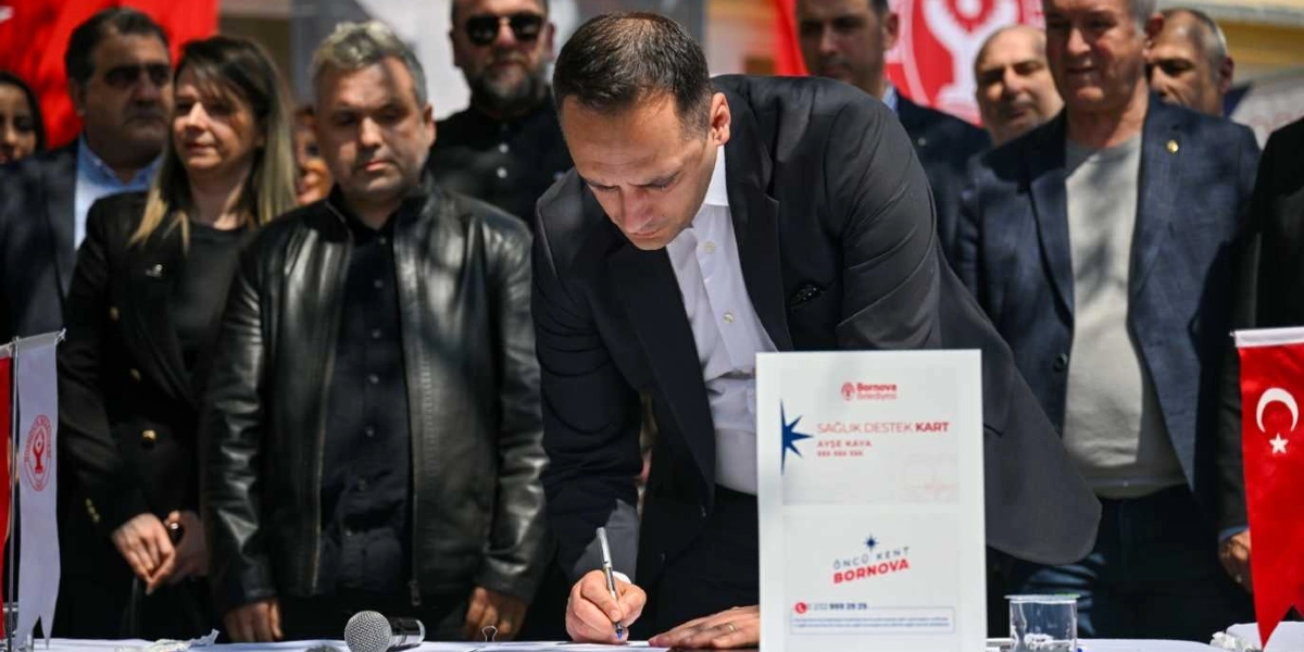 Koyu renk takım elbiseli bir erkek, Bornova Belediyesi logolu 
