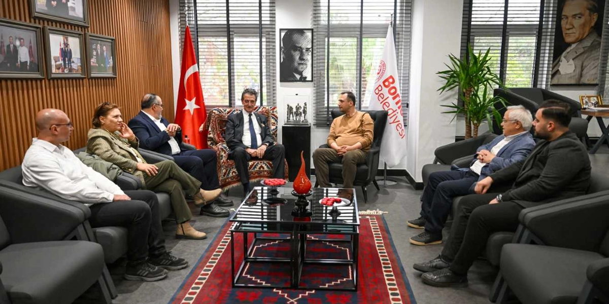 Atatürkçü Düşünce Derneği temsilcilerinin Bornova Belediyesi'nde gerçekleştirdiği ziyarette, karşılıklı koltuklarda oturan bir grup insan toplantı yapıyor. Odanın duvarlarında Atatürk portreleri, Türk bayrağı ve Bornova Belediyesi flaması yer alıyor. Ortada siyah cam tablalı bir sehpa ve zeminde geleneksel desenli bir halı bulunuyor.