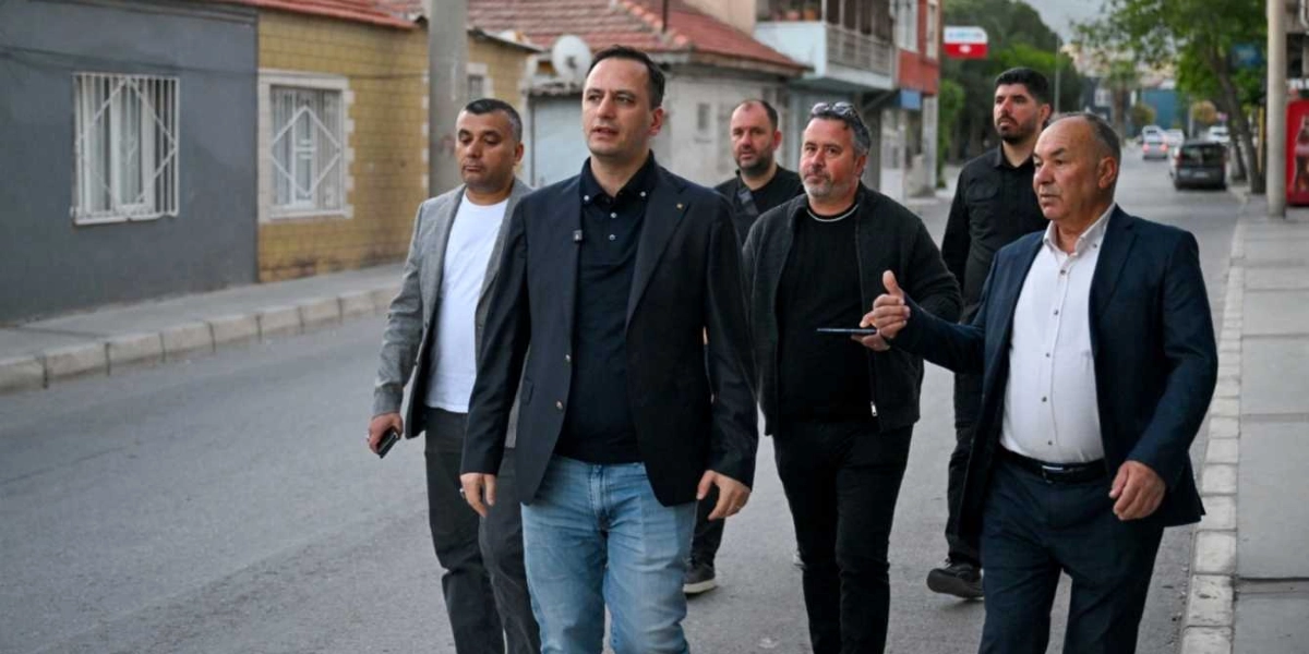 Belediye Başkanı Filiz Ceritoğlu Sengel'e benzeyen koyu renk ceketli ve açık mavi kot pantolonlu bir erkek, beraberindeki dört kişilik bir heyetle birlikte Egemenlik Mahallesi'ndeki bir sokakta yürürken görülüyor. Heyette yer alan diğer kişiler günlük ve resmi kıyafetlerle eşlik ederken, en sağdaki kişi el hareketleriyle bir şeyler anlatıyor.
