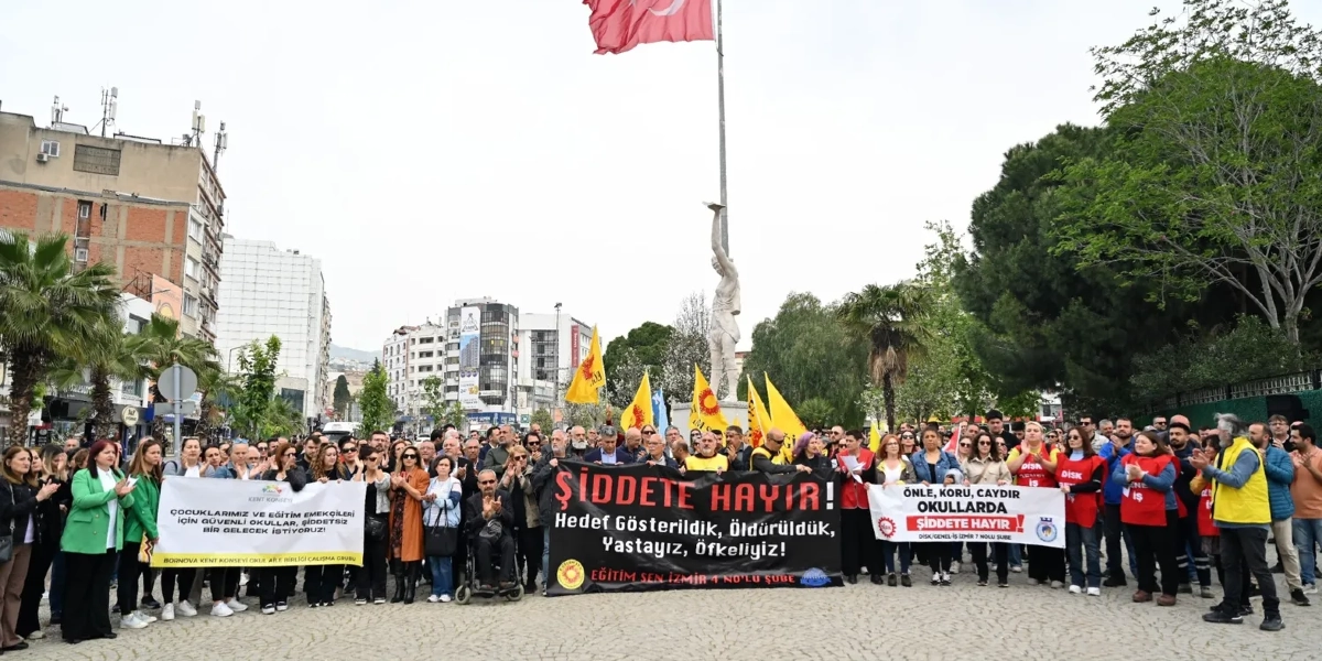 Bornova'da bir meydanda toplanan kalabalık grup, okullarda şiddete karşı protesto düzenliyor. Grubun önünde 