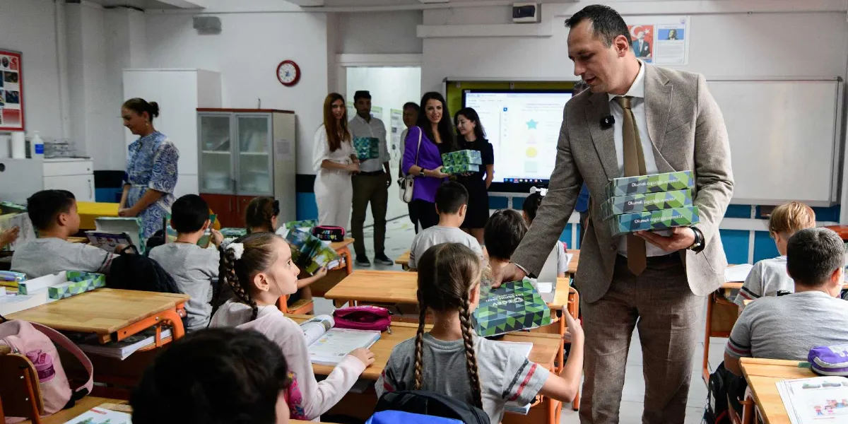 Sınıf ortamında, bej renkli takım elbiseli bir erkek, öğrencilere üzerinde 