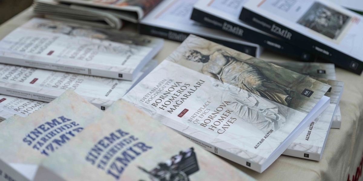 Masa üzerine dizilmiş, üzerinde Altan Altın imzası bulunan çeşitli kitaplar. Ön planda 