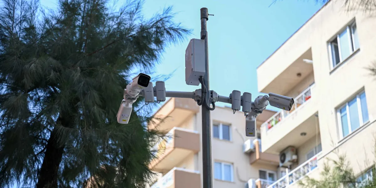 Dış mekanda, bir direk üzerine monte edilmiş çok sayıda güvenlik kamerası ve sensör cihazı. Arka planda ağaçlar ve yerleşim yerlerini andıran çok katlı binalar görülüyor.