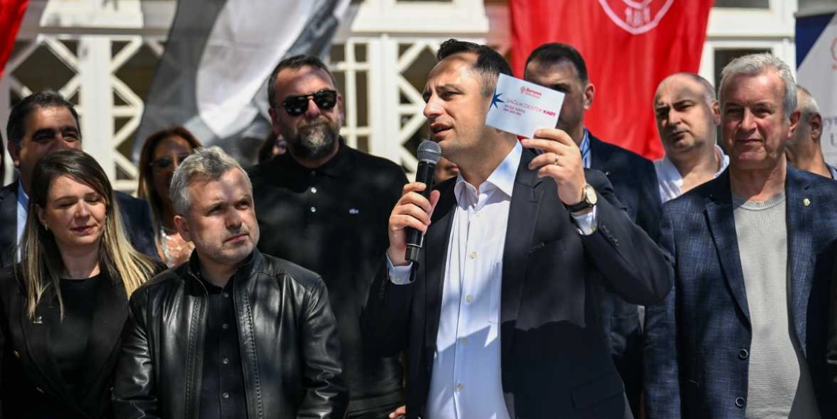 Koyu renk ceketli ve beyaz gömlekli bir erkek, elinde 