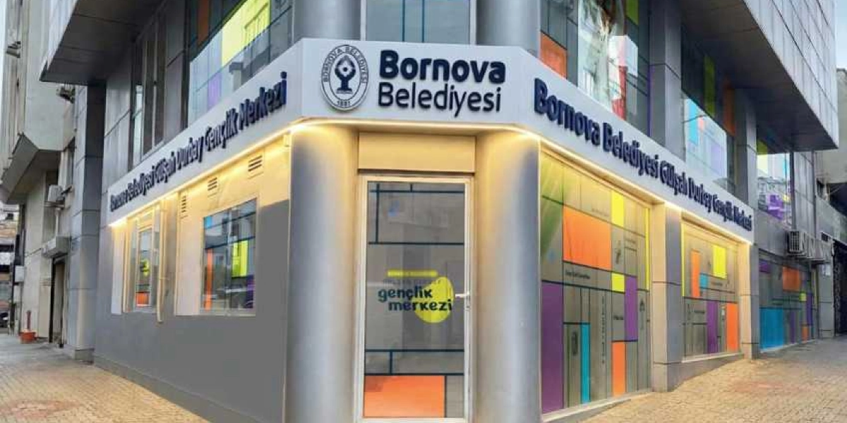 Bornova Belediyesi Gülşah Durbay Gençlik Merkezi'nin dış cephesi. Binanın köşesinde Bornova Belediyesi logosu ve ismi yer alıyor. Cam kapı üzerinde ve binanın yan cephelerinde 
