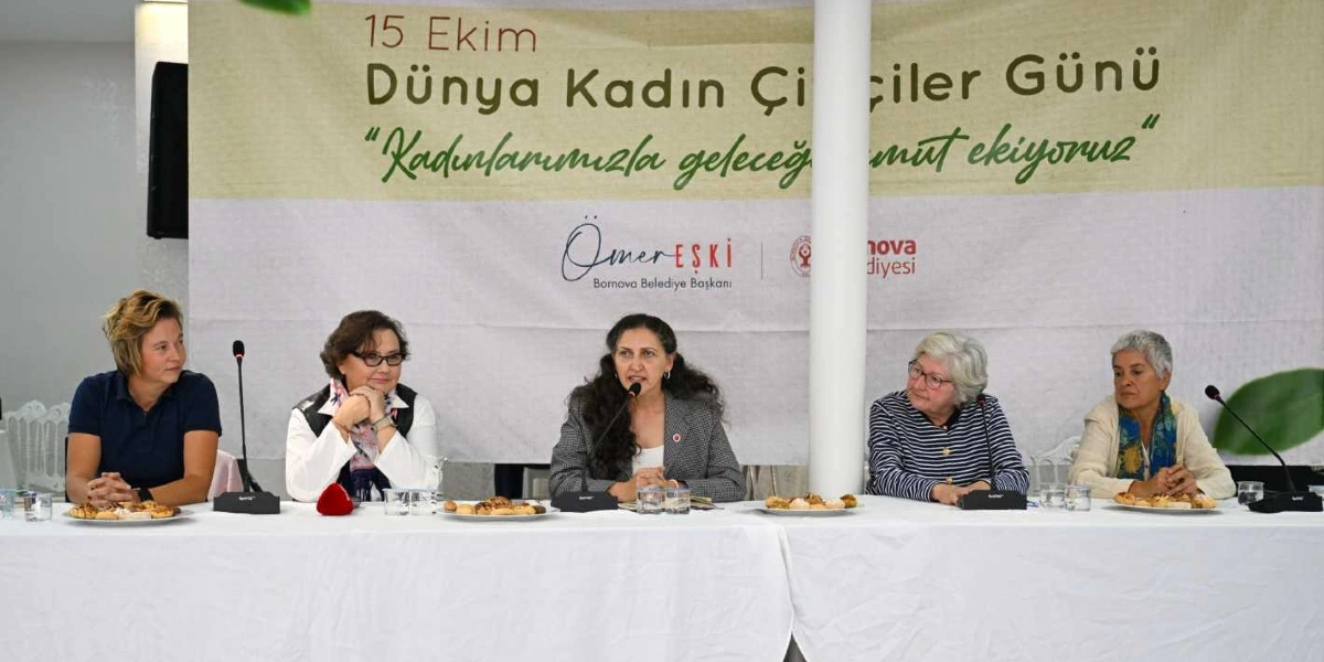 15 Ekim Dünya Kadın Çiftçiler Günü kapsamında düzenlenen bir panelde, beyaz örtülü uzun bir masada yan yana oturan beş kadın konuşmacı yer alıyor. Arka planda üzerinde 