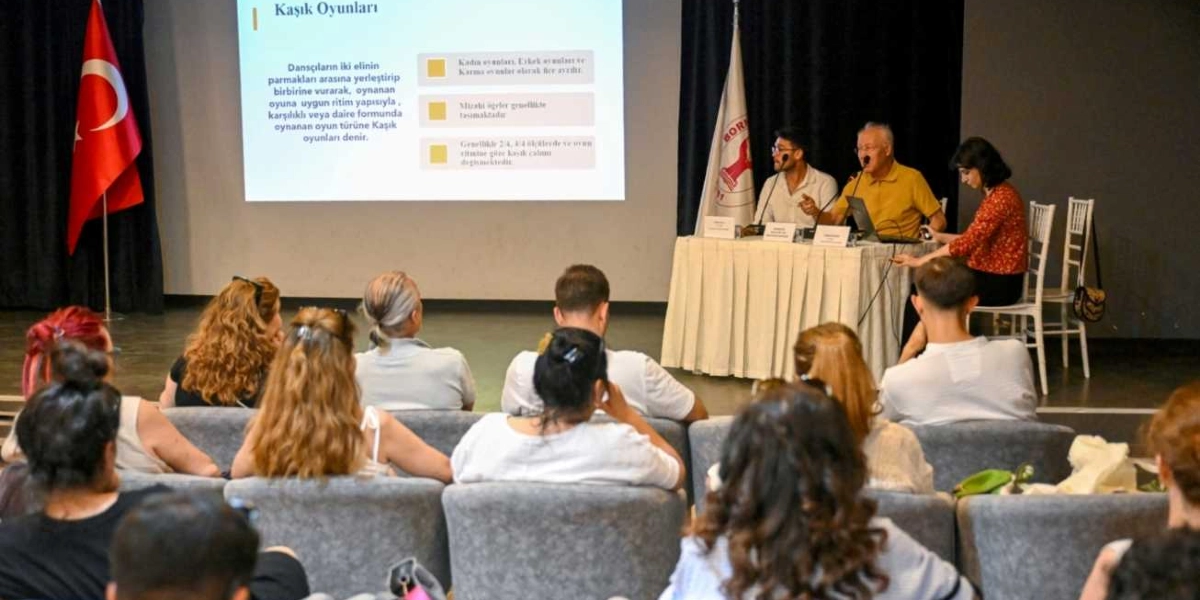 Kapalı bir salonda düzenlenen Kaşık Oyunları konulu sunumda, sahnedeki masada oturan iki konuşmacı ve bir moderatör, izleyicilere bilgi veriyor. Arkadaki projeksiyon perdesinde 