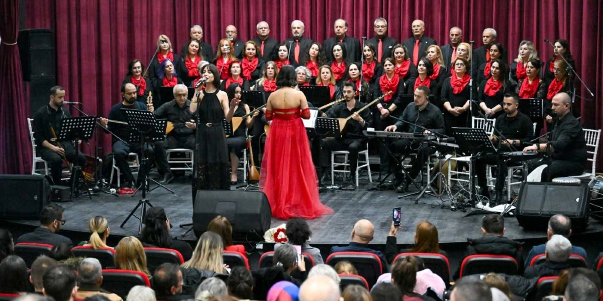 Sahne üzerinde, arkada bordo perdelerin önünde sıralanmış büyük bir koro ve önlerinde müzisyenlerden oluşan bir topluluk konser veriyor. Korodaki kadınlar siyah kıyafetlerinin üzerine kırmızı fularlar takmış, erkekler ise siyah takım elbise ve kırmızı kravat giymiş durumda. Sahnenin ön kısmında, siyah uzun bir elbise giymiş kadın solist mikrofonla şarkı söylerken, yanında kırmızı uzun bir elbise giymiş başka bir kadın ona eşlik ediyor. Müzisyenler bağlama, klavye ve çeşitli enstrümanlar çalıyor. Sahne önünde, izleyicilerin oturduğu koltuklardan çekilmiş bu karede, seyircilerin başları ve sırtları görülüyor.
