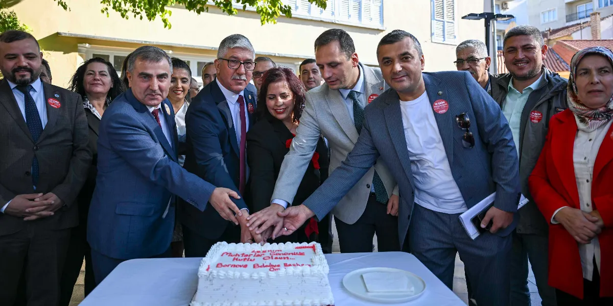Açık havada bir araya gelmiş, aralarında Bornova Belediye Başkanı'nın da bulunduğu bir grup muhtar ve yetkili, üzerinde 