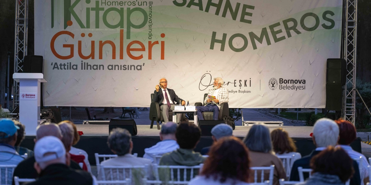 Bornova Belediyesi tarafından düzenlenen, Attila İlhan anısına gerçekleştirilen Kitap Günleri etkinliğinde, sahnede iki konuşmacı izleyicilere hitap ediyor. Arka planda 