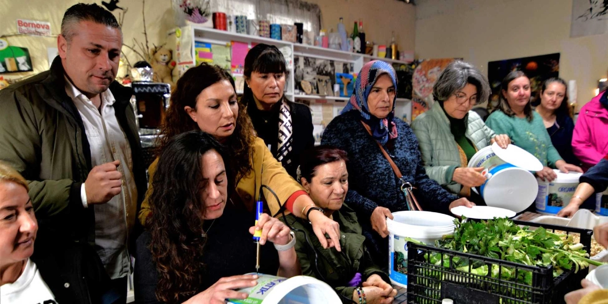 Kapalı bir mekanda bir araya gelmiş bir grup kadın ve bir erkek, üzerinde 