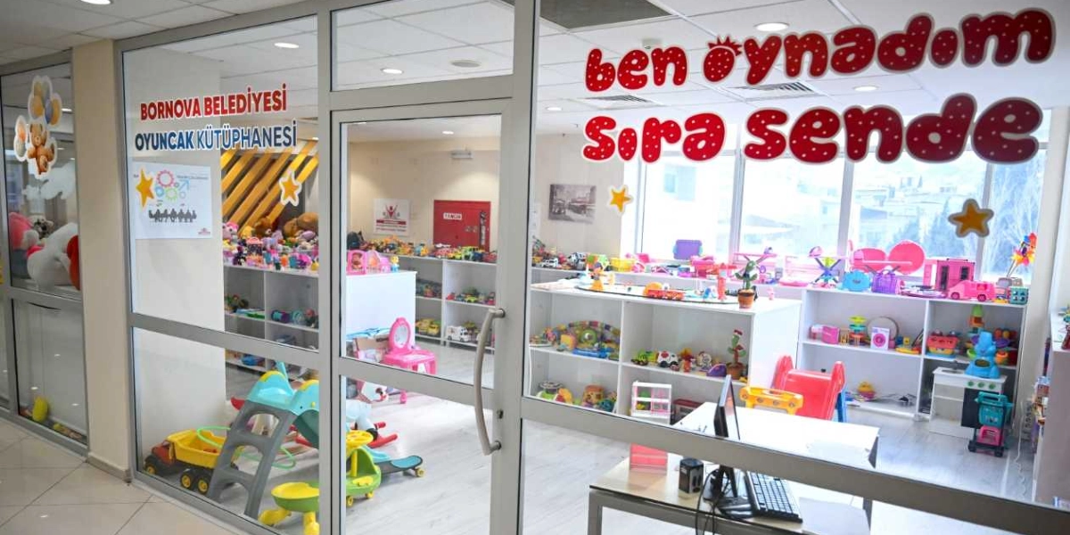 Bornova Belediyesi Oyuncak Kütüphanesi'nin cam kapılı girişi. Kapının üzerinde kırmızı puntolarla 