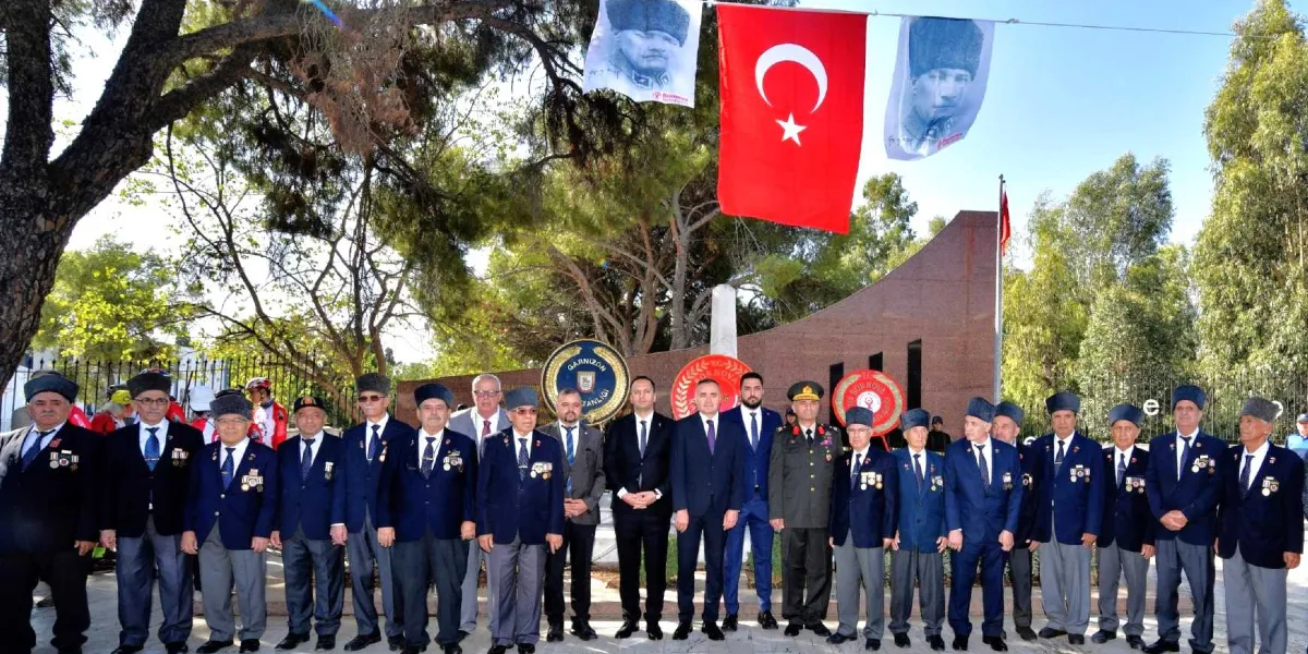 Açık havada, ağaçların önünde yan yana dizilmiş, çoğunluğu madalyalı gazilerden oluşan bir grup insan ve protokol üyeleri bir anma töreninde bir arada duruyor. Grubun üzerinde asılı olan Türk bayrağının iki yanında Mustafa Kemal Atatürk'ün portreleri yer alıyor. Arka planda Bornova Belediyesi'ne ait amblemlerin bulunduğu çelenkler ve mermer bir anıt bulunuyor. Gaziler koyu renkli takım elbiseleri ve kalpaklarıyla dikkat çekerken, yanlarında resmi kıyafetli bir askeri yetkili ve takım elbiseli sivil yöneticiler yer alıyor.