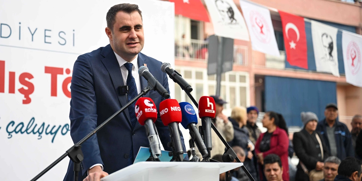 Lacivert takım elbiseli ve kravatlı bir erkek, arkasında 