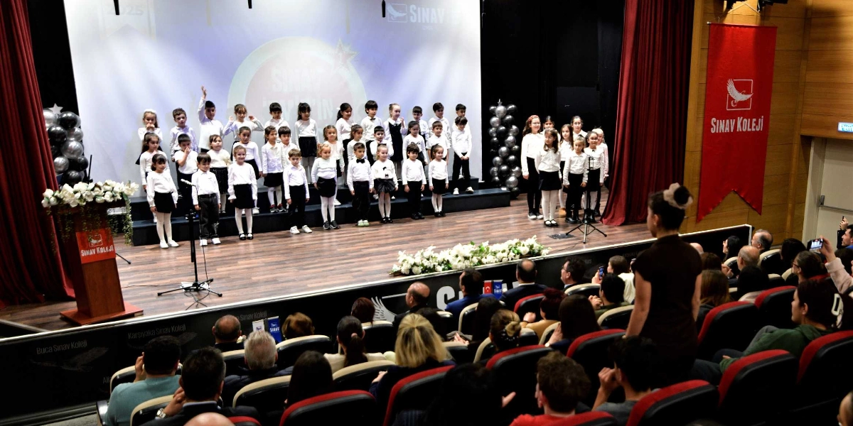 Sınav Koleji'nin düzenlediği bir etkinlikte, sahnedeki beyaz gömlekli ve siyah alt kıyafetli ilkokul öğrencileri koro halinde şarkı söylerken, izleyiciler koltuklarda oturarak onları izliyor. Sahnenin solunda üzerinde Sınav Koleji logosu bulunan bir kürsü, sağ tarafında ise kırmızı bir flama yer alıyor. Sahne arkasındaki büyük ekranda okulun logosu ve ismi görülüyor, sahnenin iki yanında ise siyah balon süslemeleri bulunuyor.