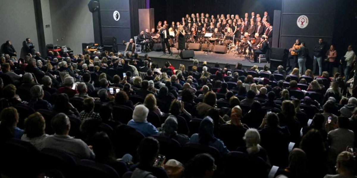 Bornova Belediyesi'ne ait bir kültür merkezinde gerçekleşen konserde, sahne üzerinde siyah kıyafetli geniş bir koro ve orkestra üyeleri performans sergiliyor. Sahnenin önünde bir kadın ve bir erkek solist mikrofon başında şarkı söylüyor. Salonu tamamen dolduran izleyiciler, sahneye dönük bir şekilde oturarak konseri izliyor. Sahne duvarlarında Bornova Belediyesi'nin amblemleri yer alıyor.
