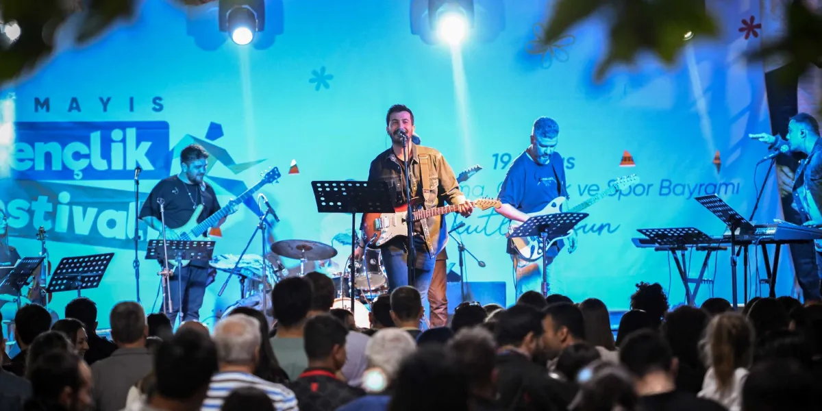 Mavi ışıklarla aydınlatılmış bir sahnede konser veren müzik grubu ve onları izleyen kalabalık bir izleyici kitlesi. Grubun solisti elinde gitarıyla şarkı söylerken, yanında bas gitar çalan bir müzisyen ve klavye başında başka bir sanatçı yer alıyor. Sahne arkasındaki dev ekranda 