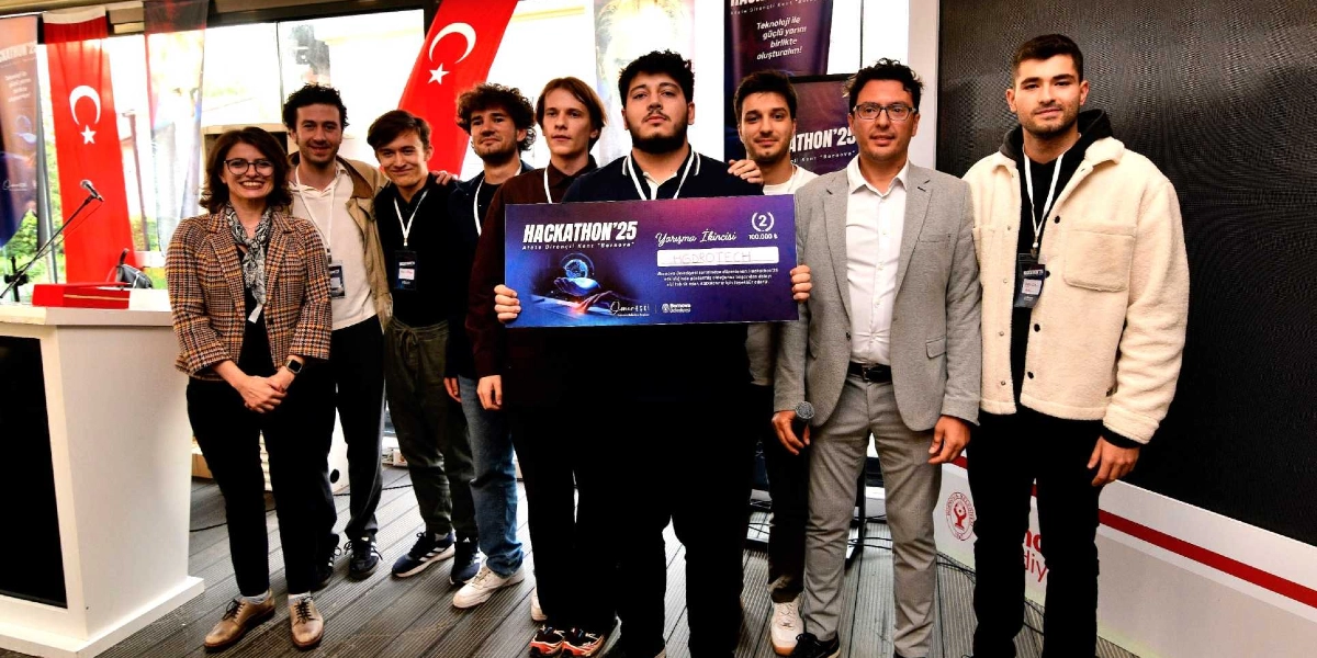 Hackathon'25 yarışmasında ödül kazanan bir grup genç ve bir yetkili, ellerinde 