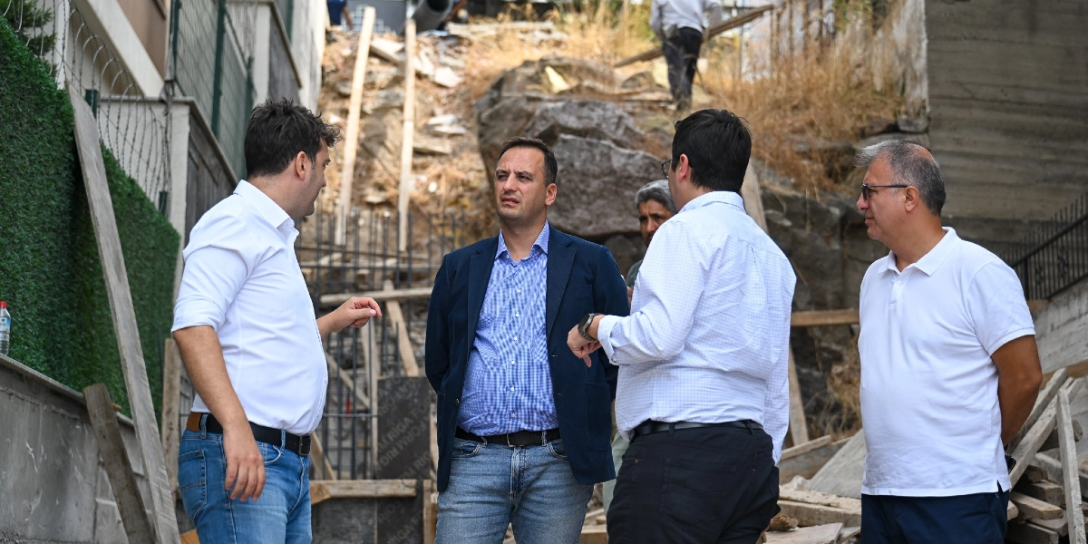 Bornova'da devam eden bir merdiven inşaatı alanında incelemelerde bulunan dört erkek, şantiye ortamında bir arada durarak sohbet ediyor. Arka planda toprak zemin, inşaat kalıpları ve merdiven yapım çalışmaları görülüyor.