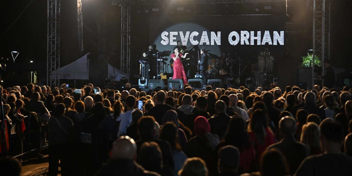 Gece vakti açık havada düzenlenen bir konserde, kırmızı elbiseli şarkıcı Sevcan Orhan sahnede orkestrasıyla birlikte şarkı söylüyor. Sahne arkasındaki dev ekranda ışıklı harflerle Sevcan Orhan yazısı yer alıyor. Sahne önünde ise konseri izleyen kalabalık bir seyirci grubu bulunuyor.