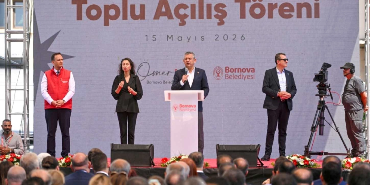 CHP Genel Başkanı Özgür Özel, Bornova Belediyesi'nin düzenlediği 15 Mayıs 2026 tarihli toplu açılış töreninde kürsüde konuşma yapıyor. Özel'in yanında bir işaret dili tercümanı ve Bornova Belediyesi yetkilileri bulunurken, sağ tarafta bir kameraman çekim yapıyor. Arka planda üzerinde 