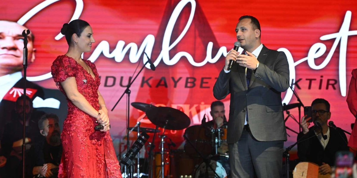 Kırmızı çiçekli uzun bir elbise giymiş bir kadın ve koyu renk takım elbiseli bir erkek, arkalarında Atatürk silüeti ve 