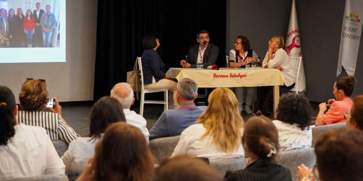 Bornova Belediyesi tarafından düzenlenen Engelli Hakları Çalıştayı'nda, bir panel masasında oturan dört konuşmacı ve onları dinleyen bir izleyici grubu yer alıyor. Panel masasının önünde 
