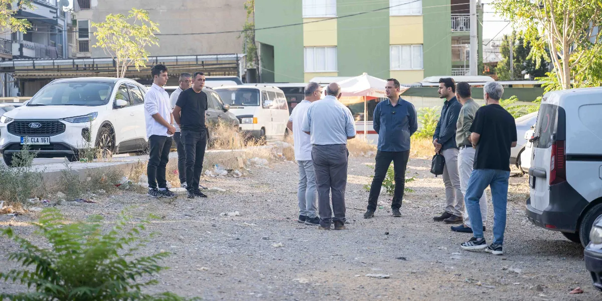 Bornova'da boş bir arazide bir araya gelmiş, aralarında sohbet eden sekiz kişilik erkek grubu. Gruptakiler gündelik kıyafetler içinde, etraflarında park halindeki araçlar ve arka planda apartmanlar bulunuyor.