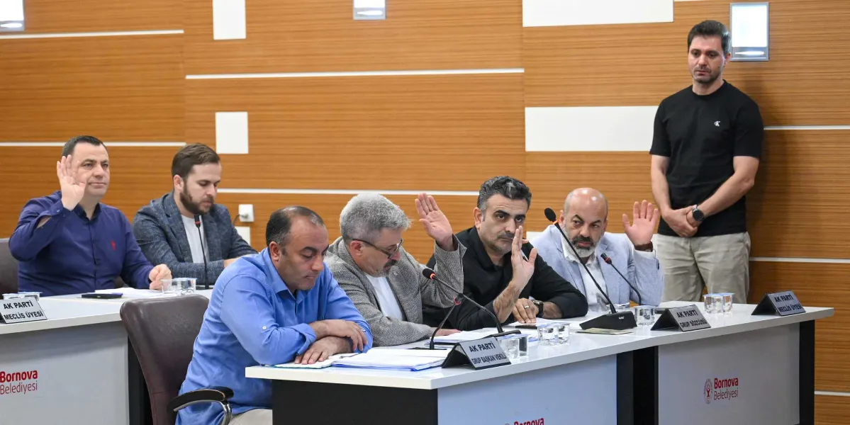 Bornova Belediyesi meclis salonunda, masada oturan ve ellerini kaldırarak oylamaya katılan AK Parti grubu üyeleri. Masaların üzerinde 