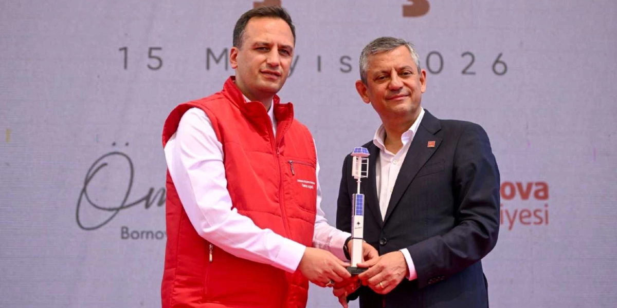 Bornova Belediye Başkanı Ömer Eşki, üzerinde güneş panelleri bulunan küçük bir yenilenebilir enerji santrali maketini Cumhuriyet Halk Partisi Genel Başkanı Özgür Özel'e takdim ediyor. Arka planda üzerinde 